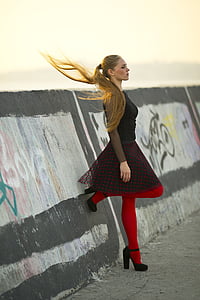 woman wearing black and red dress standing near concrete wall at daytime