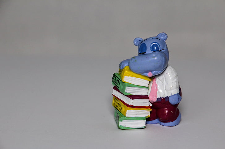 blue hippopotamus leaning on books table figurine