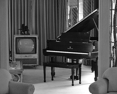grayscale photography of upright piano near television