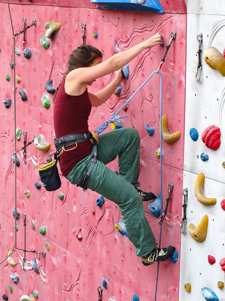photo of woman in red tank top doing wall climbing