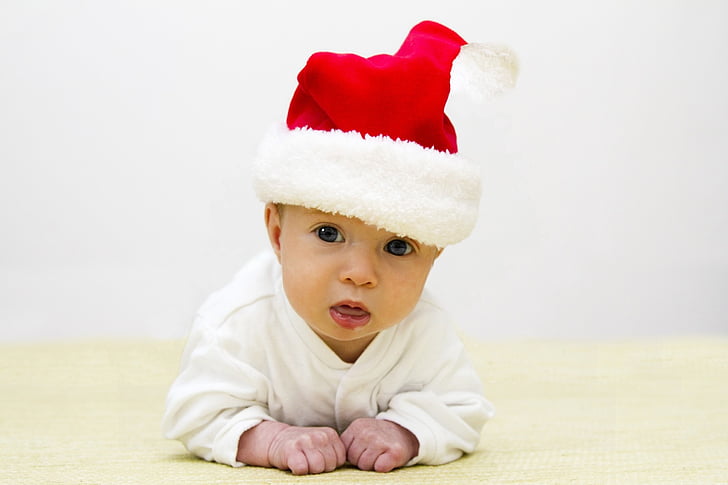 baby wearing red Santa hat crawling on floor