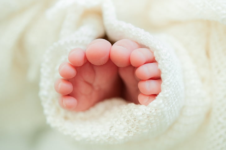 baby's feet on white textile