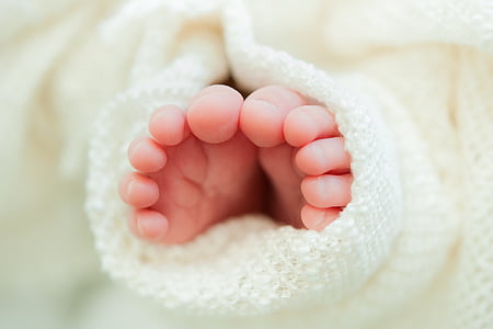 baby's feet on white textile