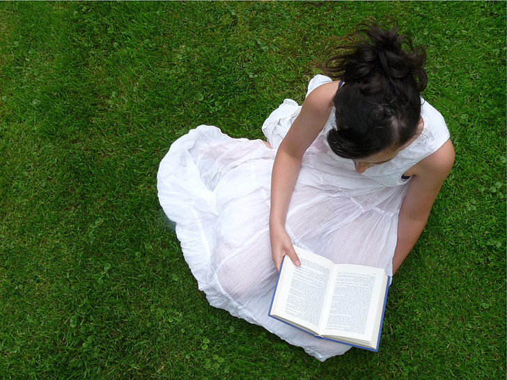 woman seating on grass reading book