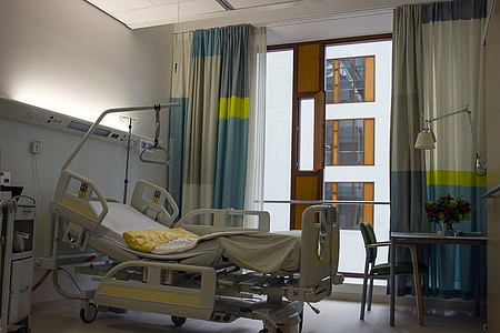 gray hospital bed near blue and gray window curtain inside room