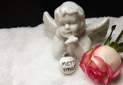 white angel ceramic figurine beside pink rose