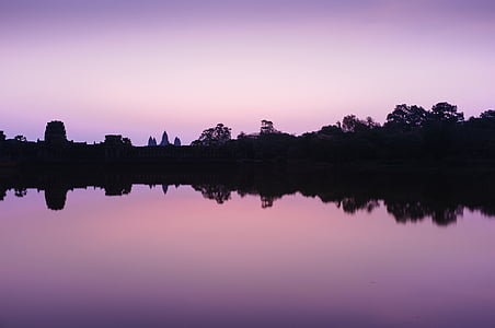 silhouette of buildings near calm body of water at sunset