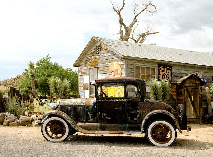 photography of black Ford Model A near gray house