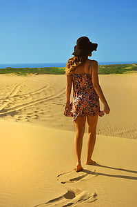 woman wearing bucket hat standing on sand
