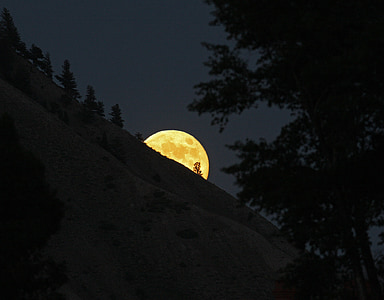 photo of hill covering half face of moon