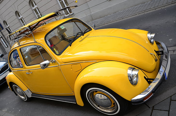 yellow Volkswagen Beetle couple on roadway near gray building