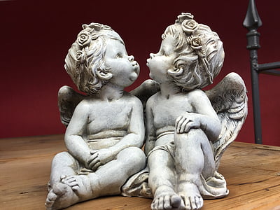 two cherub kissing each other concrete statuette on wooden surface