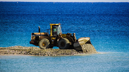 photo of yellow front-end loader near body of water