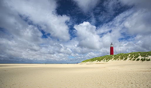 in distant photo of red lighthouse on landscape beach