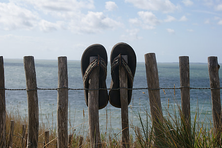 black flip-flops on fence in daytime