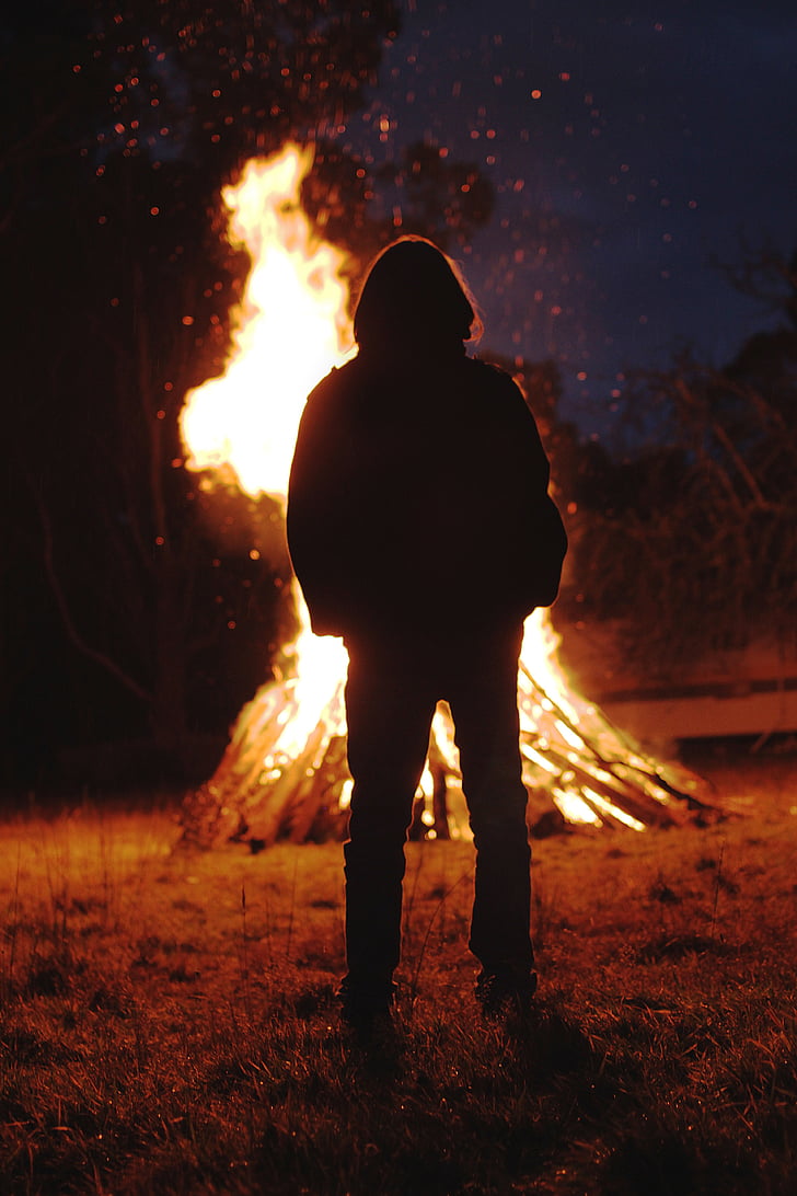 silhouette of person standing in front of bonfire