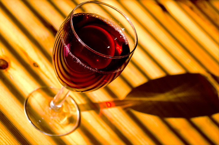 photography of footed glass with wine