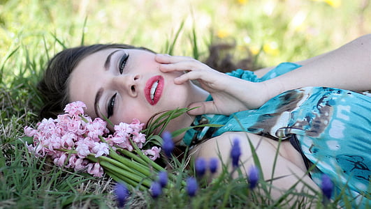 woman laying on grass field with flowers