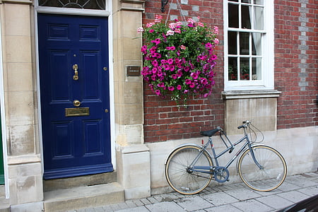 bicycle parked next to house with blue door ]