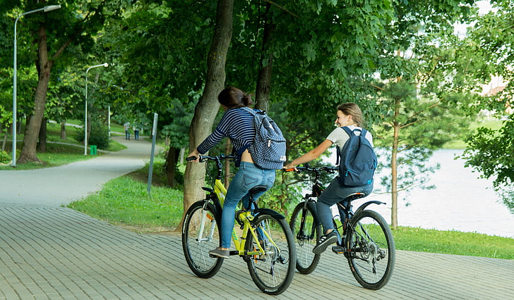 two women riding on mountain bikes on street during daytime