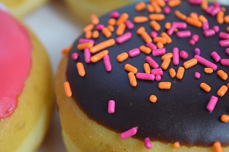 black icing-covered donut with pink and orange springkles