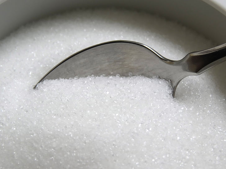 gray stainless steel spoon on white sugar powder