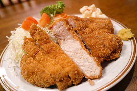 breaded chicken with white ceramic plate on brown table