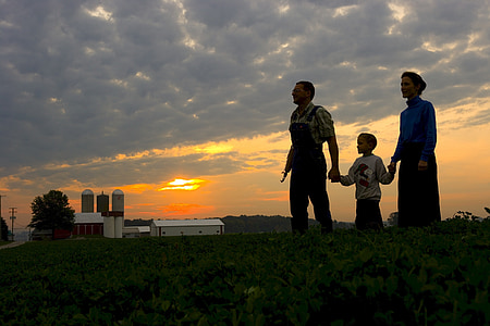 silhouette of a family standing at the hill in a distance of factory under cloudy sky