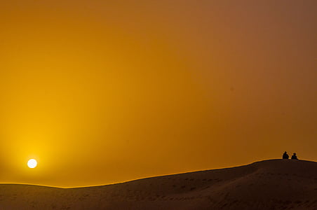 silhouette photography of two person at desert under sunsert