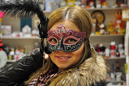 woman in black and pink masquerade mask near white shelf