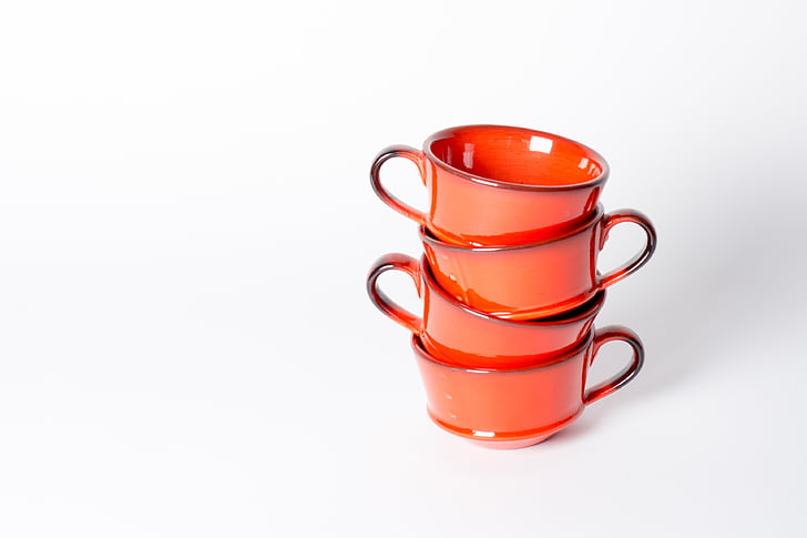 four orange ceramic cups on white surface