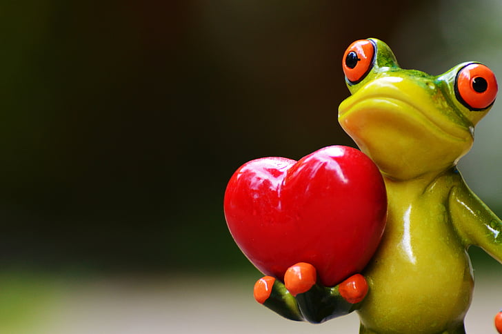 ceramic green frog carrying heart selective focus photography