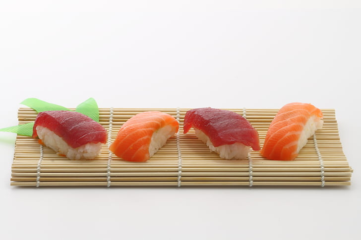 four salmon sushi on brown wooden mat