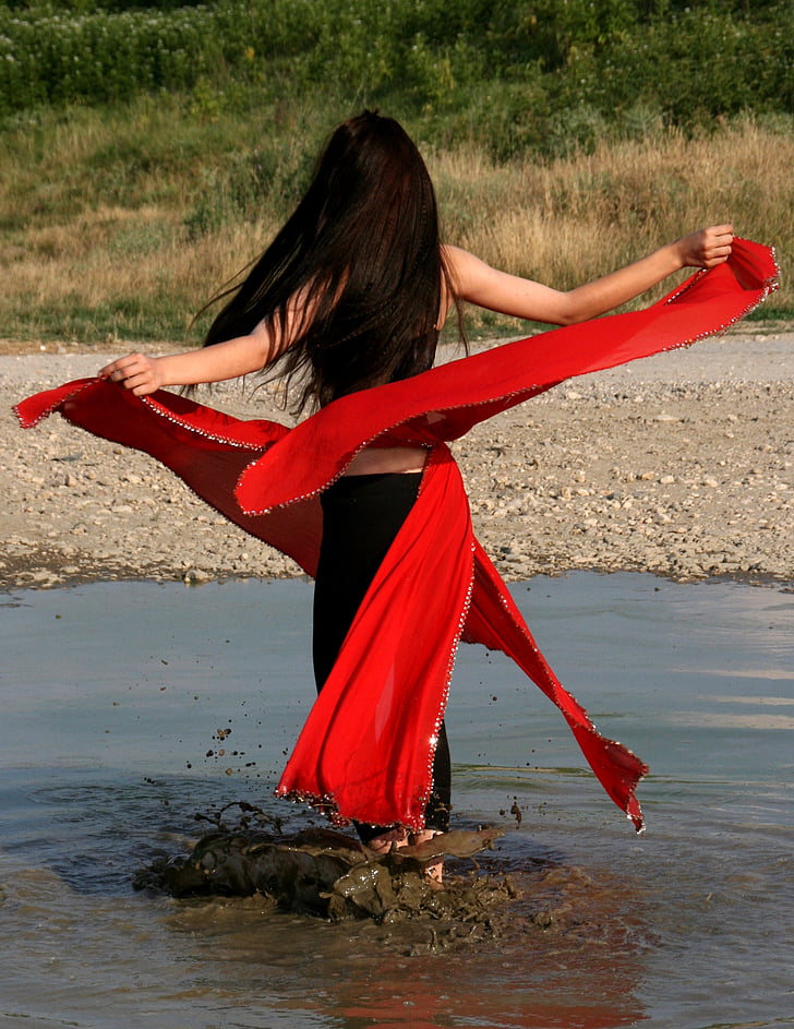 woman wearing black and red dress on brown body of water