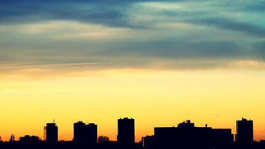 silhouette of buildings under blue and yellow skies during sunset