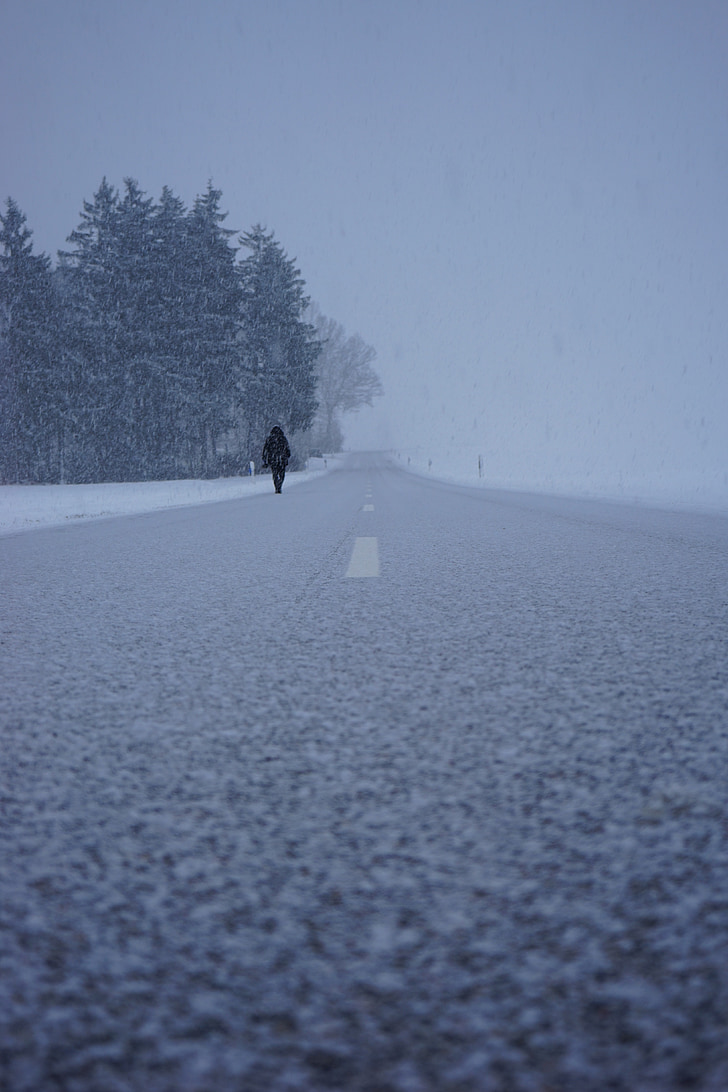 person walking on concrete road during winter