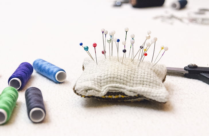 pin cushion beside threads and scissors