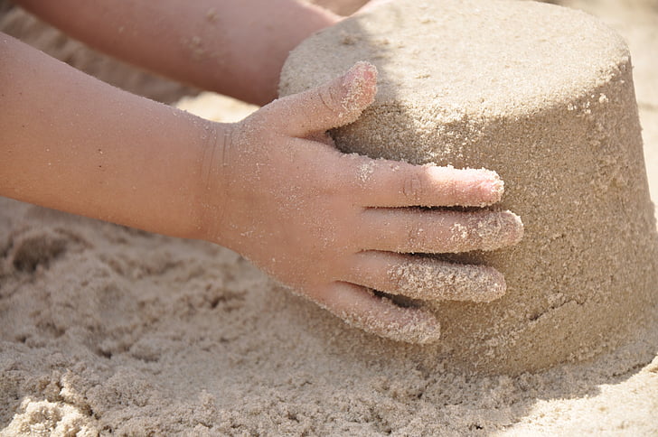 child holding pile of sand