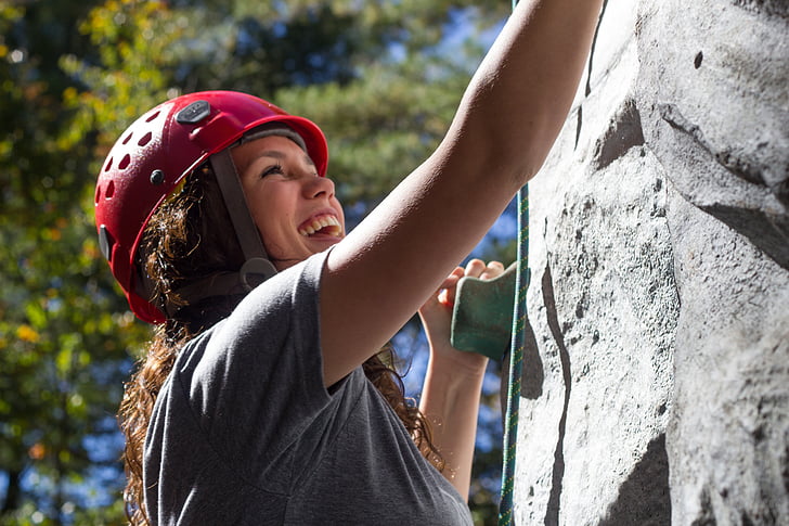 woman in gray shirt climbing on gray wall