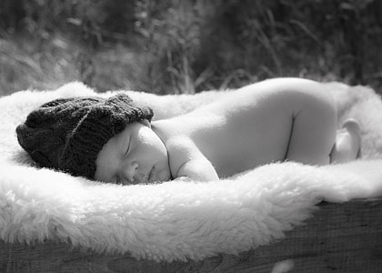 baby wearing cap lying on fleece mat