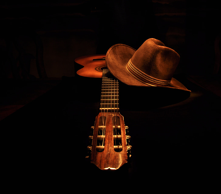 brown classical guitar and cowboy hat