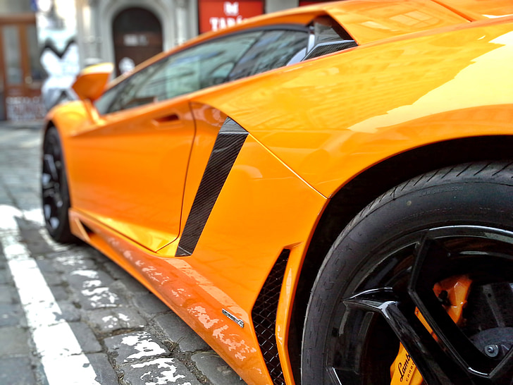 orange Lamborghini parked during daytime