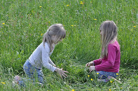 two girl seating on field of grass