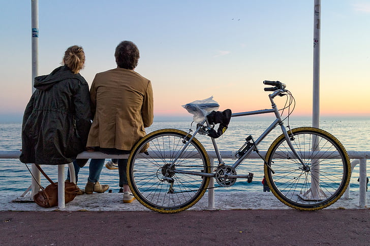 man and woman sitting on bench near bicycle