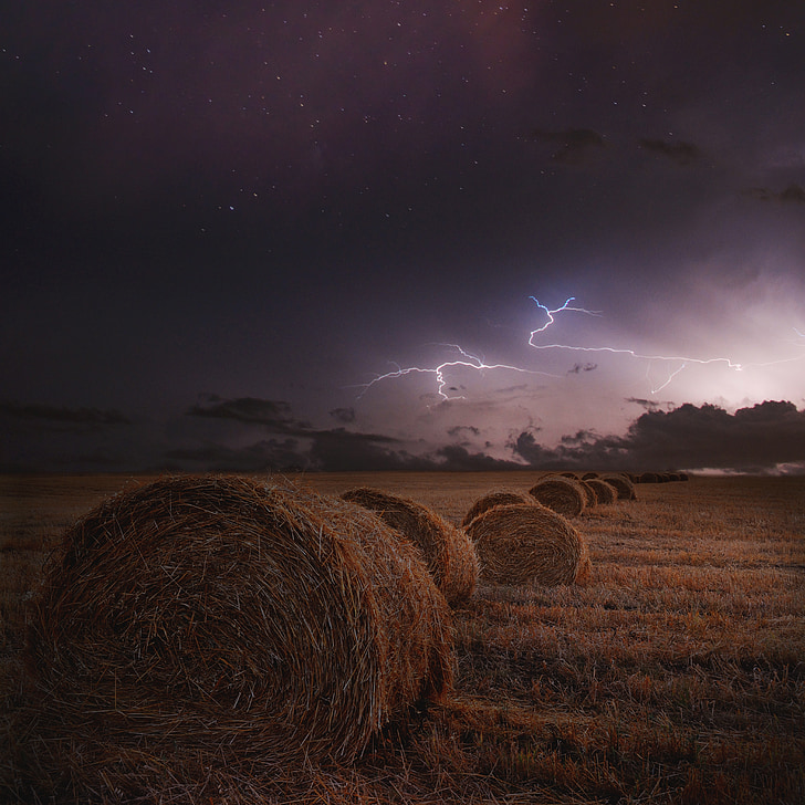 pile of rolled haystack under lightning and clouds
