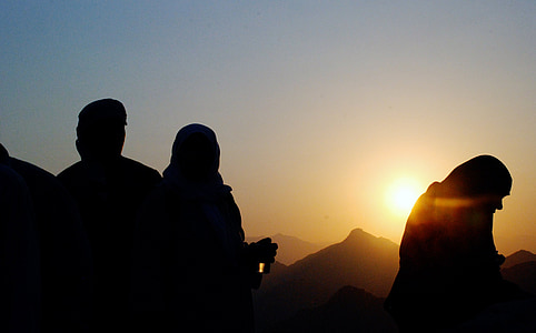 silhouette photo of people standing near mountains during sunset
