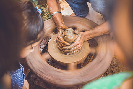 person making clay pot during daytime