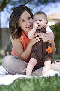 woman sitting ground holding her child during daytime