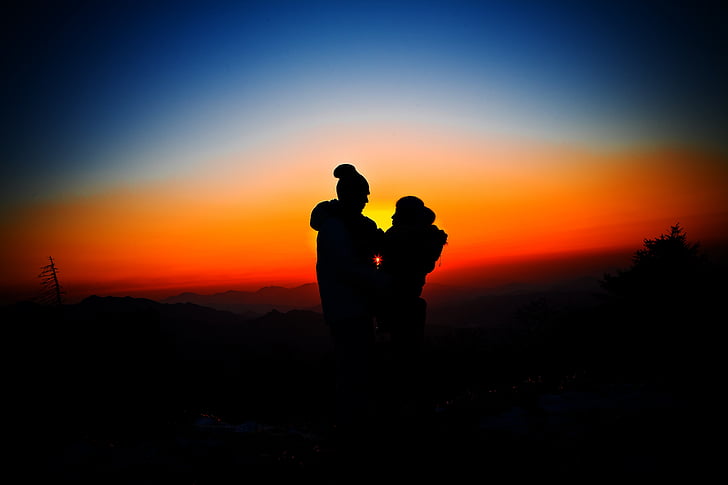 silhouette of man and woman overlooking sunset