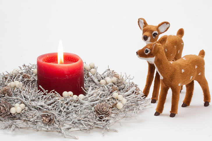 red pillar candle and two brown deer figurine